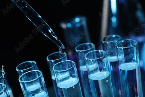 Cuadro en lienzo Dripping reagent into test tube on black background, closeup