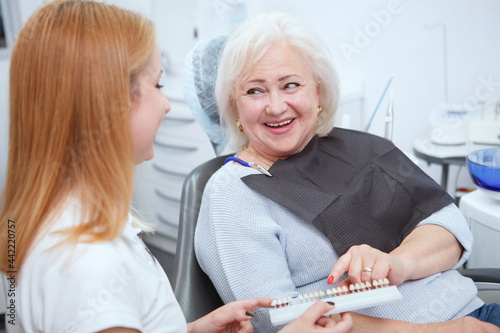 Cheerful senior woman laughing joyfully, talking to her dentist