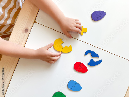 The child collects puzzles. Educational wooden toy for teaching. Montessori materials. Fine motor skills, hand-eye coordination. Children's leisure, nursery. Yoke in the form of colored eggs. Training