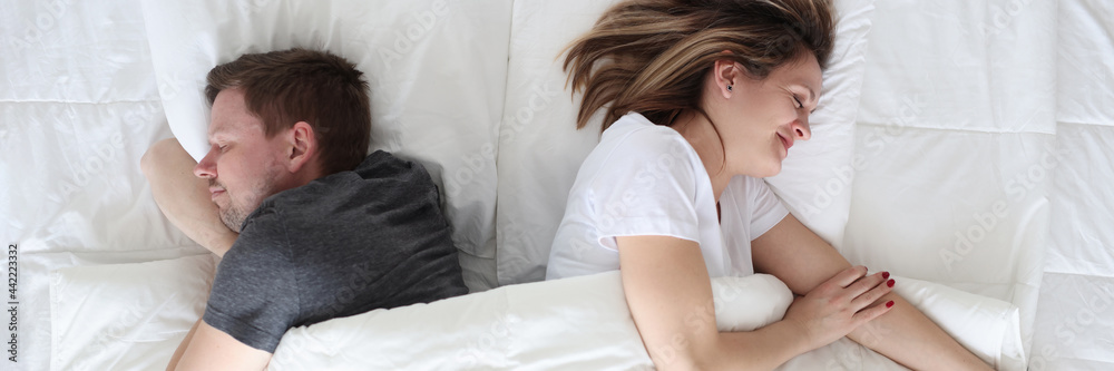 Young man and woman lying under covers top view