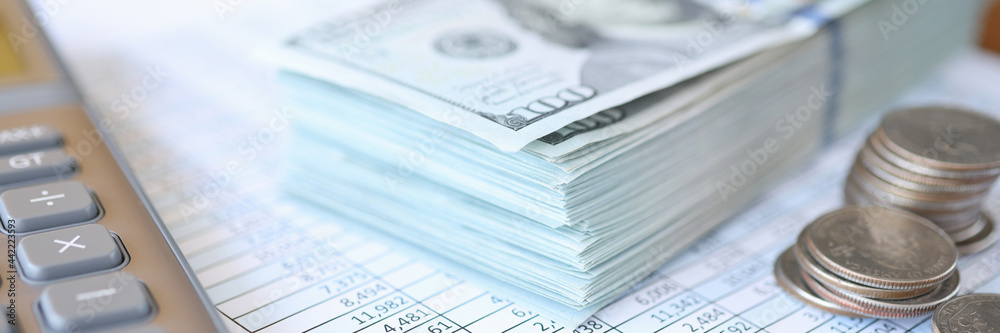Dollar bills and coins lying on documents with numbers closeup Dollar bills and coins lying on documents with numbers closeup