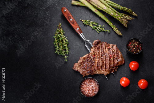 Delicious juicy fresh beef steak with spices and herbs on a dark concrete background