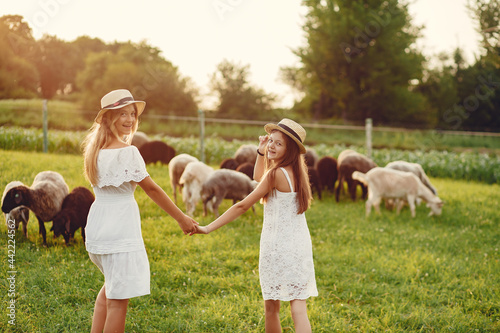 Two cute girls in a field with a goats