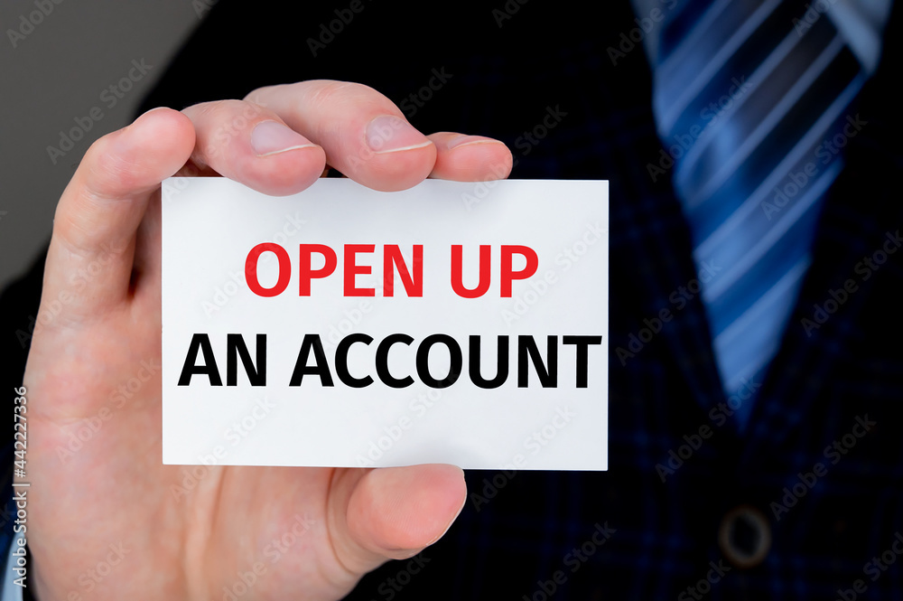 Closeup on businessman holding a card with OPEN UP AN ACCOUNT message, business concept image with soft focus background Closeup on businessman holding a card with OPEN UP AN ACCOUNT message, business concept image with soft focus background