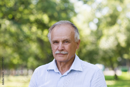 Portrait Elderly man smiling and looks in the camera outdoors. real people
