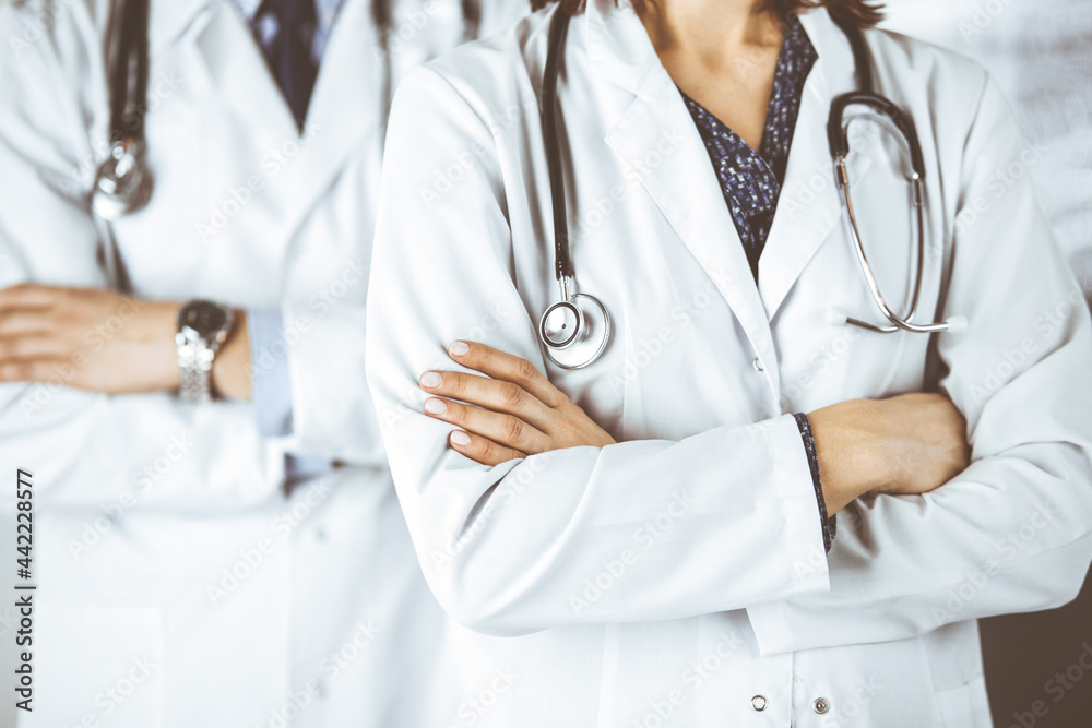 Group of modern doctors standing as a team with arms crossed in hospital office and ready to help patients. Medical help, insurance in health care, best disease treatment and medicine concept Group of modern doctors standing as a team with arms crossed in hospital office and ready to help patients. Medical help, insurance in health care, best disease treatment and medicine concept