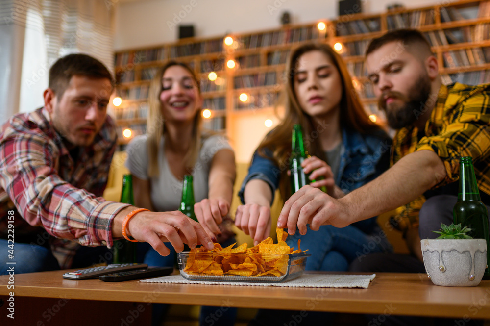 Friends eating nachos on a house party and having fun while drinking beer