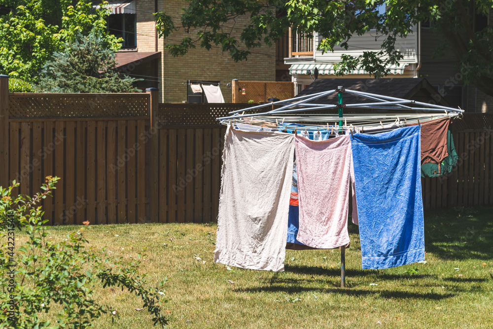 Metal outdoor clothes drying rack with towels and a shirt drying on it. On  backyard lawn. Vintage filter. Stock Photo
