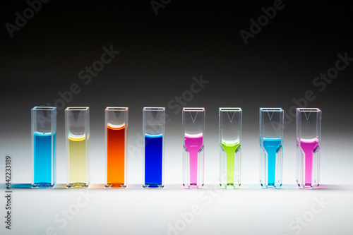 Quartz or polymer Cuvettes for photometric analysis in analytical chemistry filled with liquids of different colors on the gradient white to black background. photo