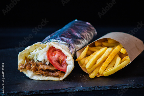Delicious durum wrapped in foil with french fries photo