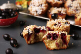 Homemade muffins with berries and streusel, sprinkled with powdered sugar on a dark gray background. Close-up