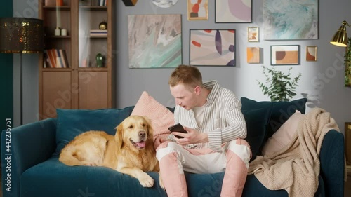 Wallpaper Mural British redhead man sitting on sofa together with dog retriever making photo or video call on camera smartphone. Positive young student man conference call with pet for blog. Torontodigital.ca