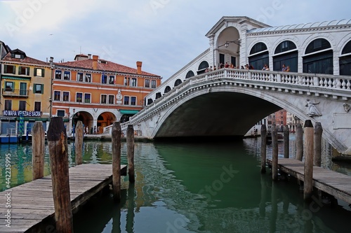 Venice, Italy. June 24, 2020. First tourists on the Rialto bridge after the lockdown for the covid-19 pandemic. In the foreground the empty piers on the grand canal.