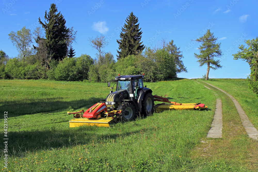Obraz premium Ein Landwirt in Bayern mäht im Sommer das Gras auf einem Feld