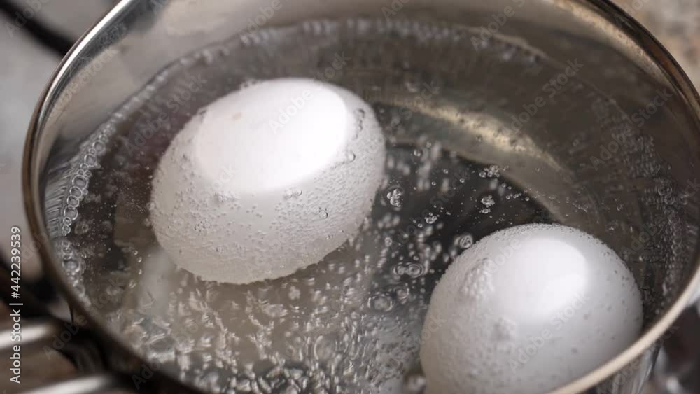 Two white eggs are boiled in pot of water. Beginning of boil.. High quality FullHD footage Two white eggs are boiled in pot of water. Beginning of boil.. High quality FullHD footage