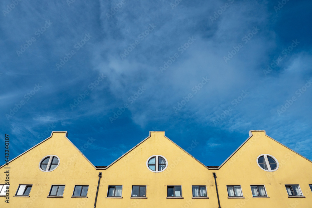 Facade of a yellow residential building against rich blue sky. Warm and cool color pallet combination