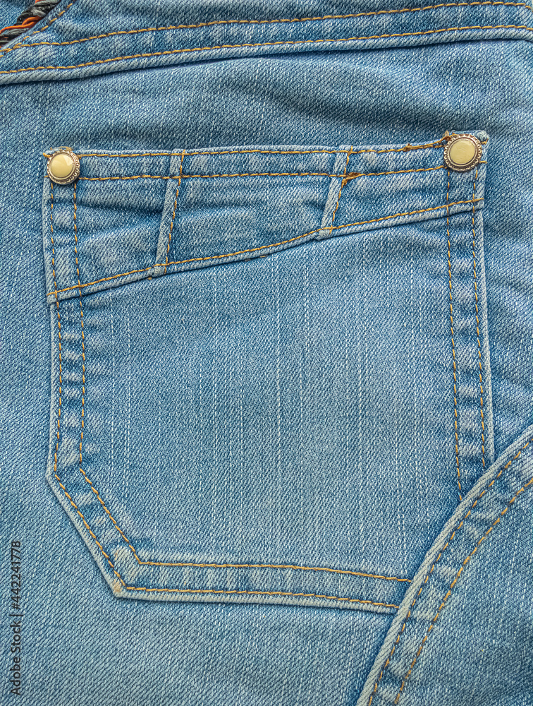Back pocket with buttons and stitching stripes on light blue jeans Back pocket with buttons and stitching stripes on light blue jeans