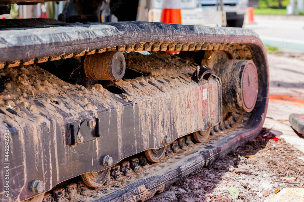 Rubber tracks on an excavator with dirt and mud covering the components