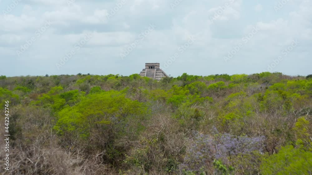 Low forwards flight over tree tops to Temple of Kukulcan - El Castillo. Historical monuments of pre-Columbian era, Chichen Itza, Mexico. Low forwards flight over tree tops to Temple of Kukulcan - El Castillo. Historical monuments of pre-Columbian era, Chichen Itza, Mexico.