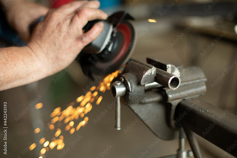 A man is working on a part in the garage.Metal grinding. Steel processing with power tools. A man is working on a part in the garage.Metal grinding. Steel processing with power tools.