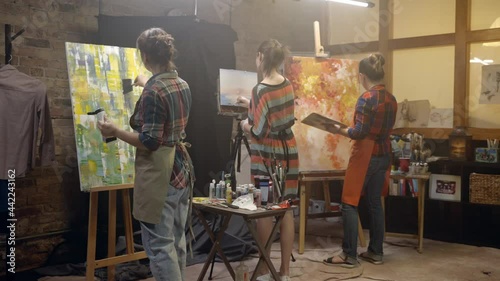 Women artists are drawing on canvases with a brush. Painting Workshop.