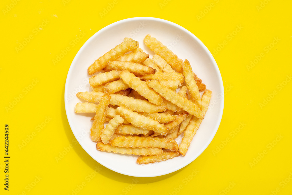 French fries in white plate on yellow background. French fries in white plate on yellow background.