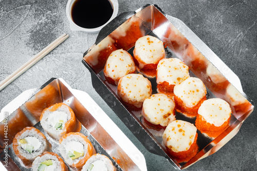 Japanese food concept. Catering, various kinds of sushi philadelphia rolls and baked prawn rolls, on gray stone background