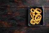 Deep fried calamari rings pack, on old dark  wooden table background, top view flat lay, with copy space for text