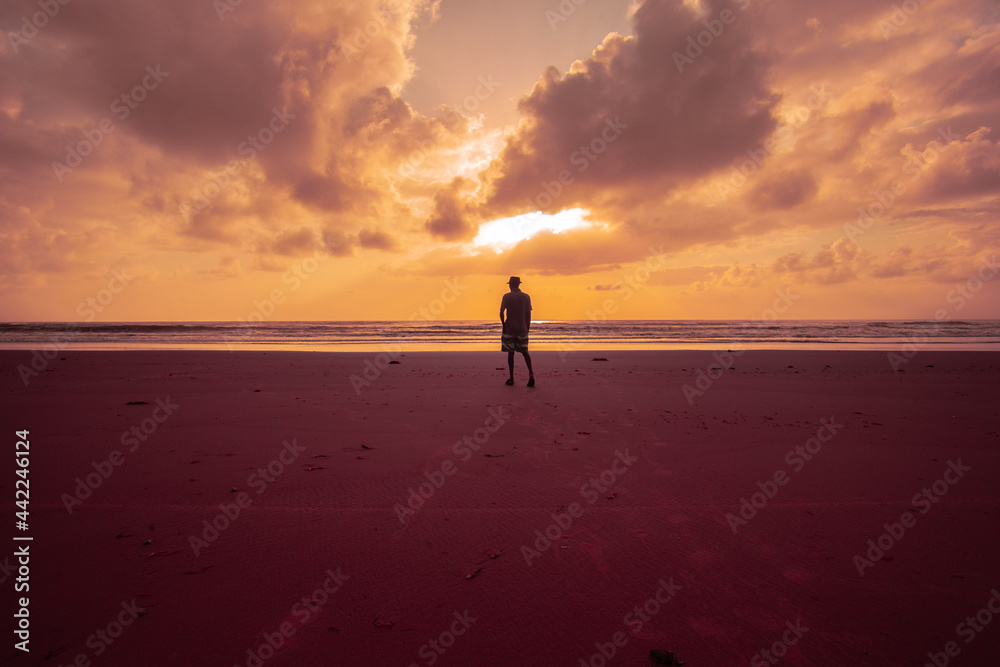 person walking on the beach at sunrise