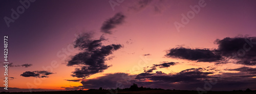 Dramatic panorama of late sunset with dark clouds and purple sky