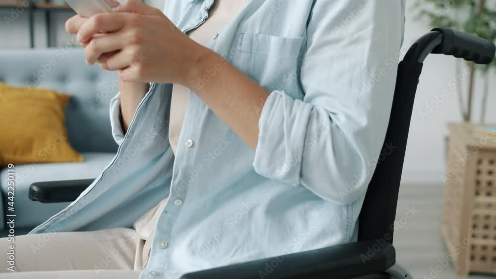 Slow motion of attractive young lady in wheelchair using smartphone texting smiling enjoying online communication at home. People and devices concept. Slow motion of attractive young lady in wheelchair using smartphone texting smiling enjoying online communication at home. People and devices concept.