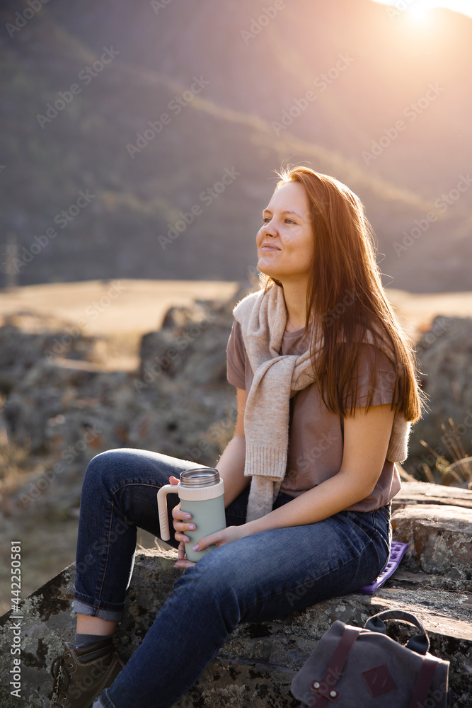 Girl traveler tourist sits on stone on  background of nature