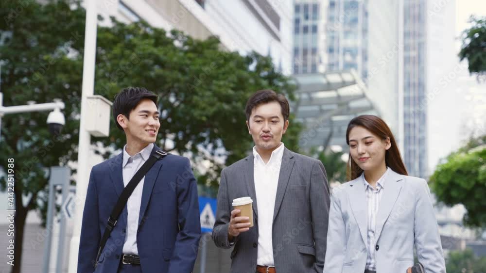 three asian business people commuters walking on street in downtown financial district of modern city three asian business people commuters walking on street in downtown financial district of modern city