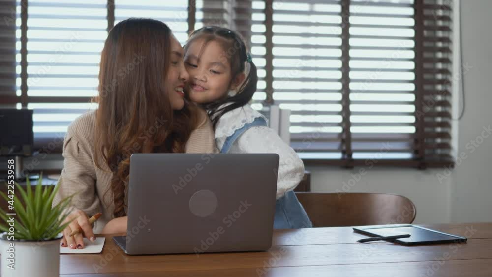 Asian young mother working with laptop computer at home his daughter help support giving shoulder massage to mother for stress relief, lifestyle freelance woman using notebook and kid help support Asian young mother working with laptop computer at home his daughter help support giving shoulder massage to mother for stress relief, lifestyle freelance woman using notebook and kid help support