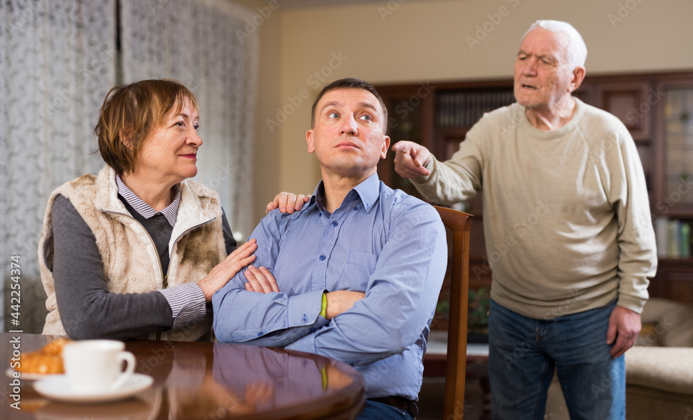 Aged parents arguing with their adult son at home. High quality photo