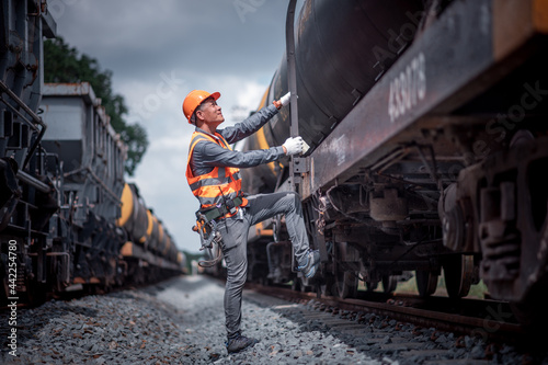 Engineer under inspection and checking construction process railway switch and checking work on railroad station .Engineer wearing safety uniform and safety helmet in work © APchanel