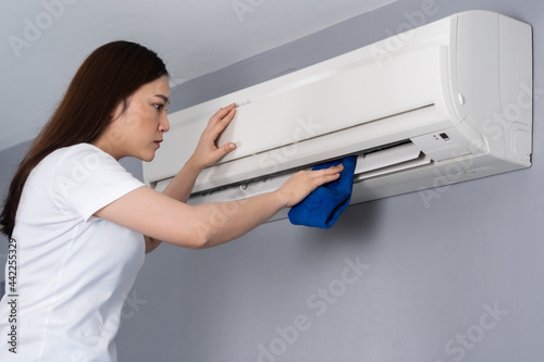 woman cleaning the air conditioner with cloth at home photo