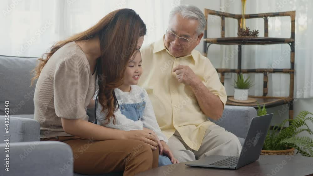 Happy family senior grandfather, daughter and granddaughter talking online via video chat using laptop computer with father, old grandpa embracing little grand child and mother in living room at home