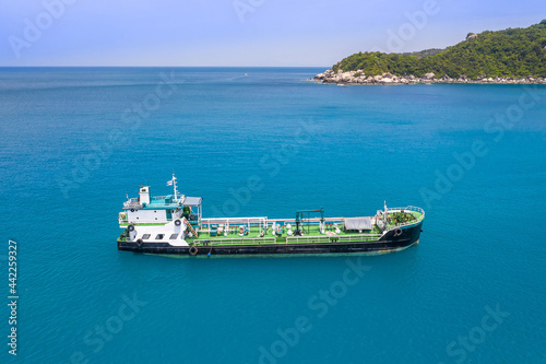 Small green container ship on a blue sea ocean no people and copy space aerial ariel drone uav view 