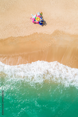 Inflatable toy seller on the beach drone aerial ariel uav top down birds eye view of beach scene sunny happy copy space and no people yellow sand green sea waves crash