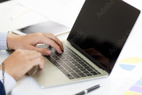 Laptop on office tablen with business man's hand in navy blue suit typing . Concept for cool style workplace photo