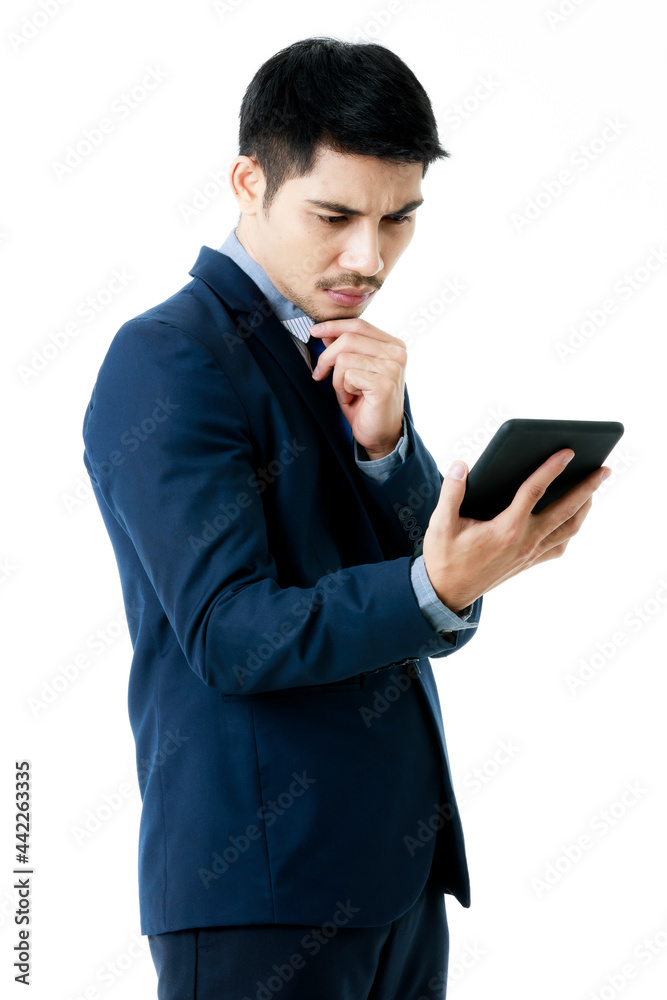 Portrait of serious young Asian businessman in thinking pose while checking company strategy on tablet on isolated white background. Studio shot, business planning concept. Portrait of serious young Asian businessman in thinking pose while checking company strategy on tablet on isolated white background. Studio shot, business planning concept.
