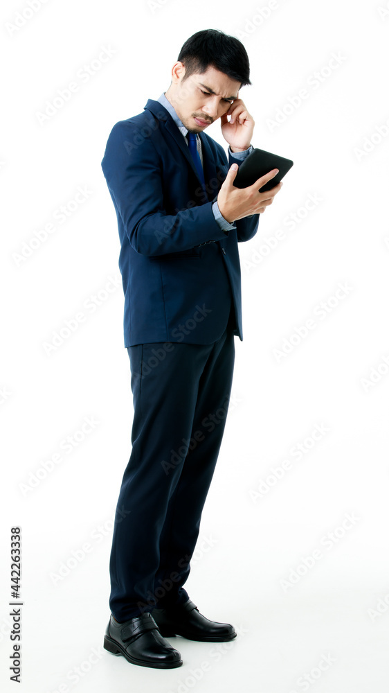Portrait of serious young Asian businessman in thinking pose while checking company strategy on tablet on isolated white background. Studio shot, business planning concept. Portrait of serious young Asian businessman in thinking pose while checking company strategy on tablet on isolated white background. Studio shot, business planning concept.
