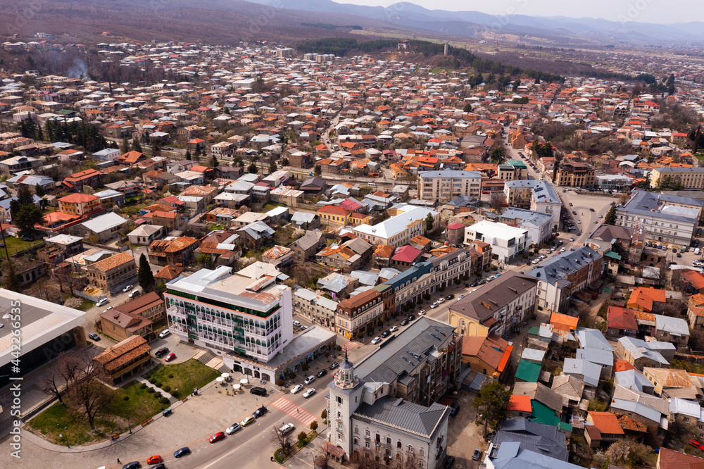 Scenic view from drone of central area of Telavi city overlooking large avenue with modern buildings surrounded by old small houses on spring day, Georgia