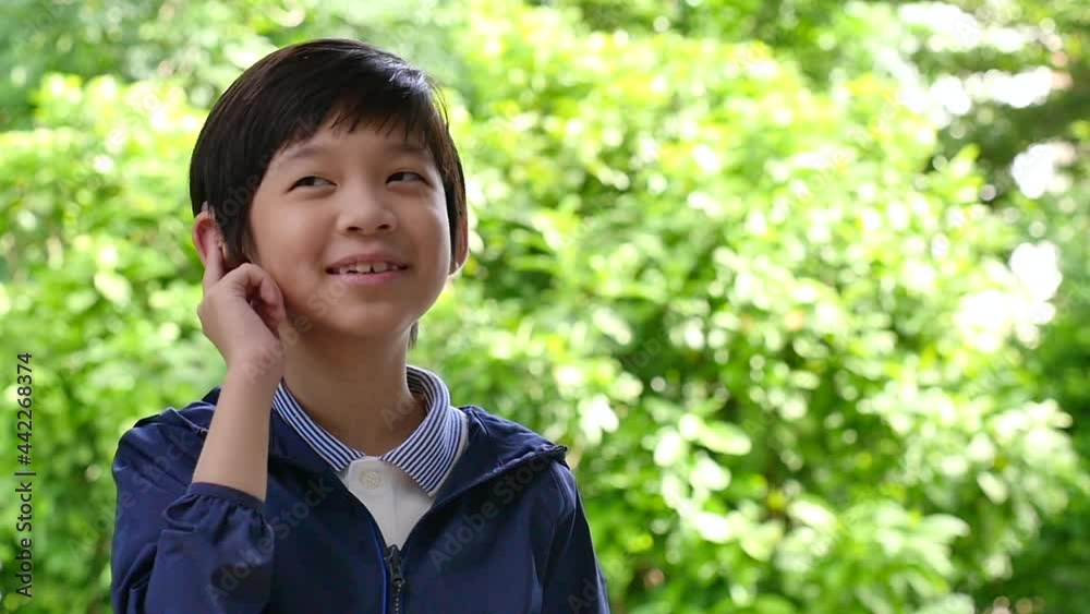 Asian Child With Hearing Aid Behind The Ear Outdoors Asian Child With Hearing Aid Behind The Ear Outdoors