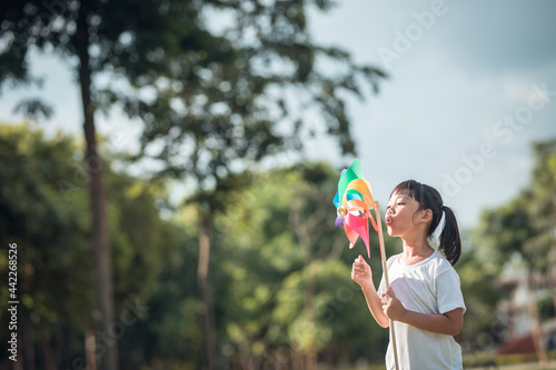 Happy Asian children girl with wind turbine in the garden