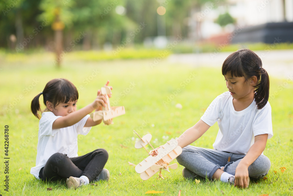 Two little kids playing with cardboard toy airplane in the park at the day time. Concept of happy game. Child having fun outdoors. Two little kids playing with cardboard toy airplane in the park at the day time. Concept of happy game. Child having fun outdoors.