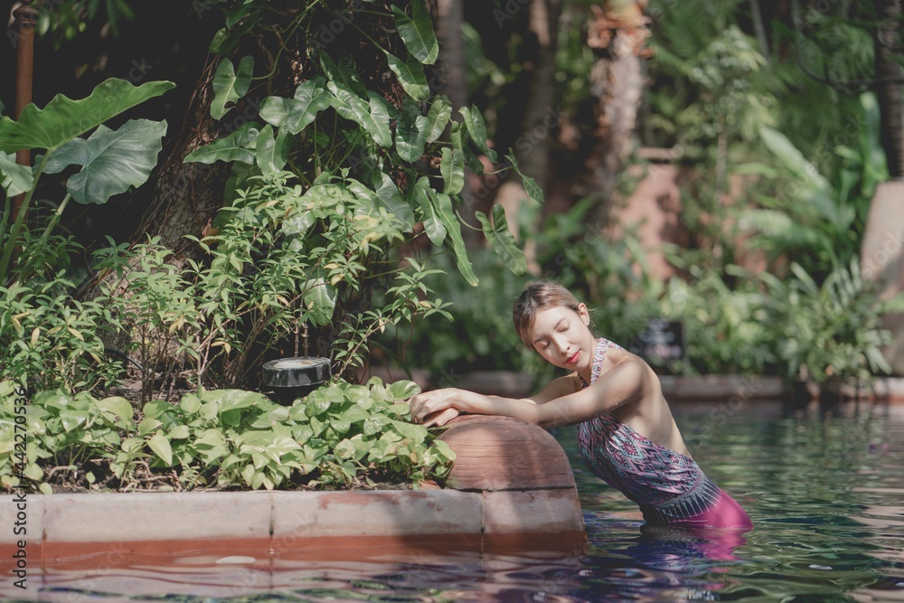 Fototapeta premium Woman in pink one piece swimsuit relax in tropical swimming pool, summer vacation.