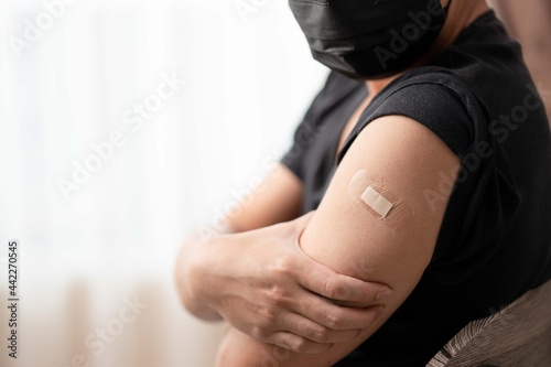 Man wearing mask arm with bandage showing his arm after receiving vaccine.