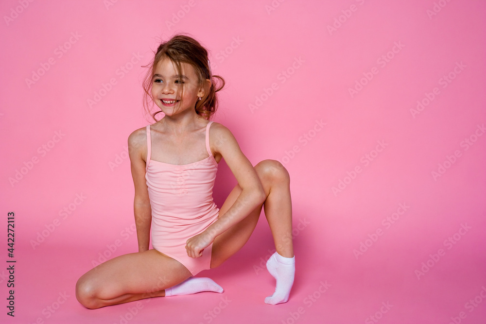 Pretty girl does gymnastics in a leotard on the pink background. children's sports concept. Pretty girl does gymnastics in a leotard on the pink background. children's sports concept.